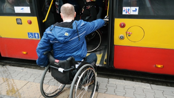 Mężczyzna na wózku wsiada do niskopodłogowego autobusu miejskiego