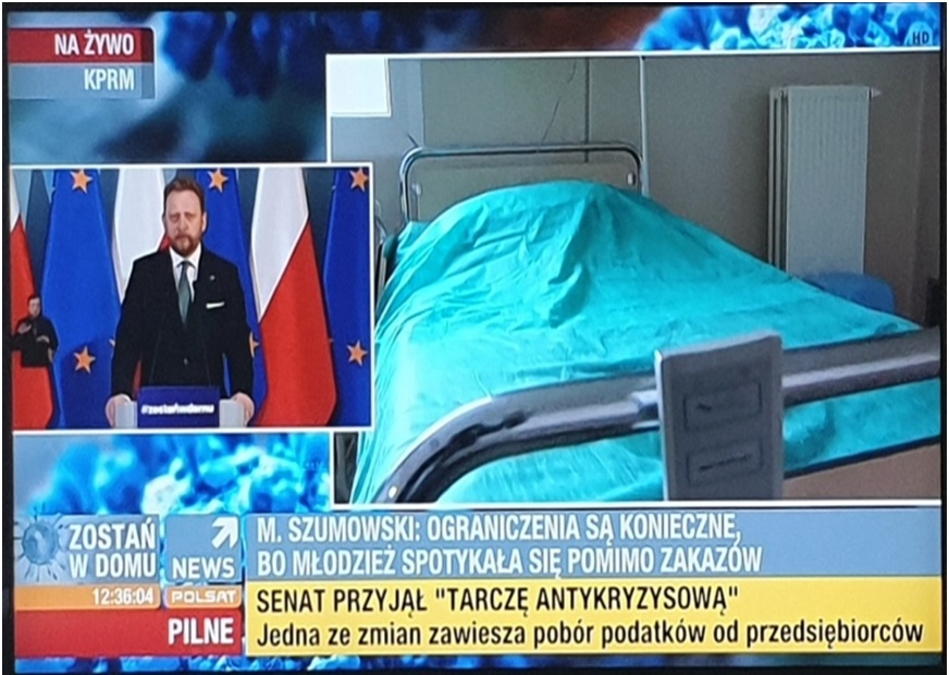 Kadr z programu informacyjnego w telewizji na temat pandemii Covid-19. Na głównym oknie jest szpitalne łóżko, w okienku bocznym pomniejszonym jest minister Szumowski, ówczesny minister zdrowia. Przy nim jest wklejony jeszcze pomniejszony tłumacz języka migowego.